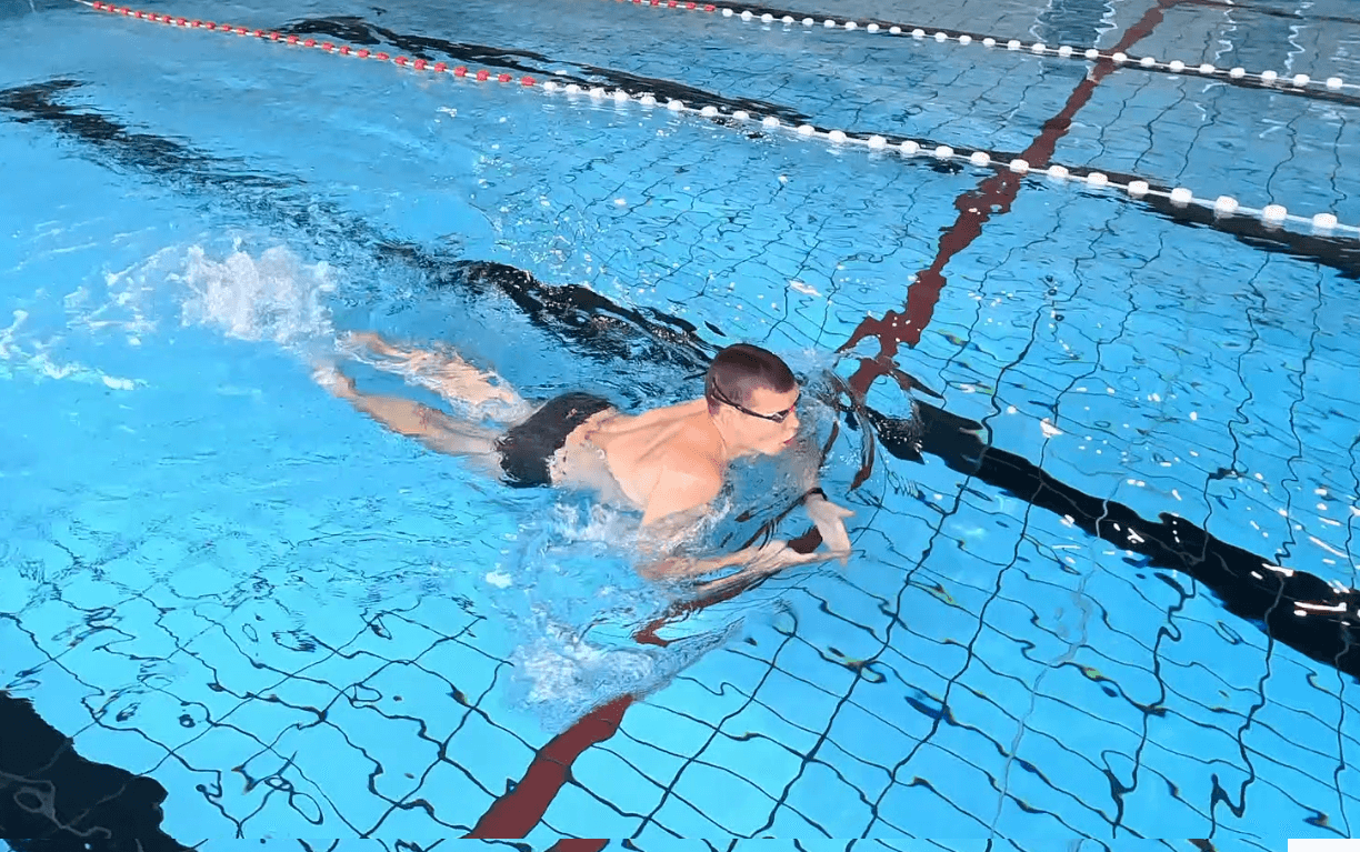 Schwimmer führt den Armzug aus, während die Beine dicht unter der Wasseroberfläche bleiben und nicht absinken.