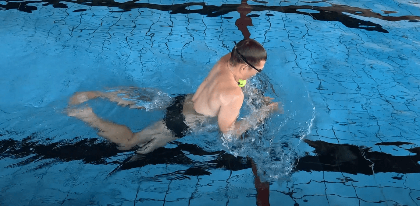 Beim Schwimmen mit einem Tennisball halte beim Anheben die Linie Hinterkopf–Rücken–Lendenwirbelsäule gerade.